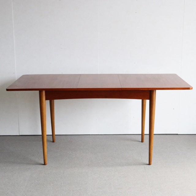 Mid-century British teak dining table with smooth rectangular top and tapered legs, showcasing fine wood grain from vintage.