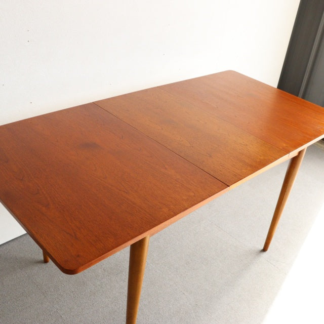 Mid-century British vintage teak dining table with smooth wood grain and tapered legs from Denmark.