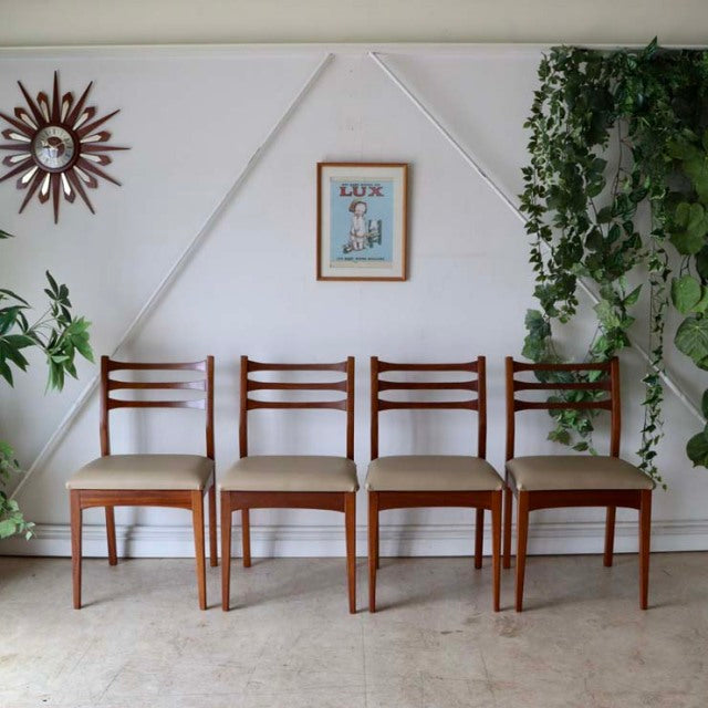 Set of four vintage mid-century teak dining chairs with British-Denmark design, featuring wood grain backs and beige.