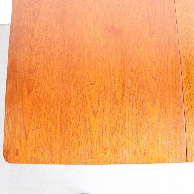Mid-century British vintage teak dining table with smooth wood grain and rounded edges.