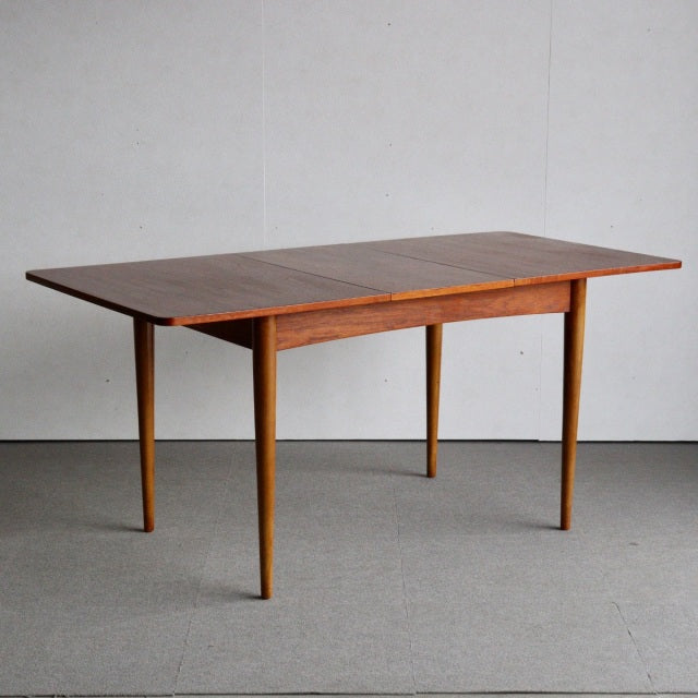 Mid-century British vintage teak dining table with rectangular top, tapered legs, and rich wood grain.