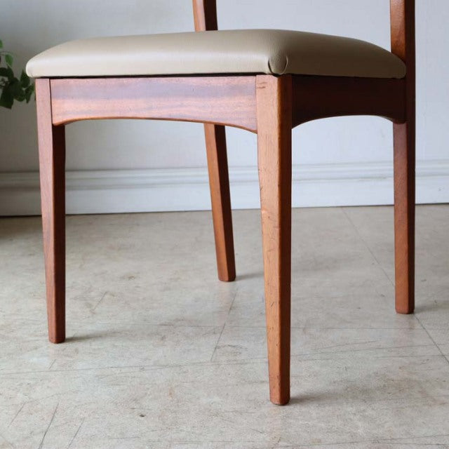 Set of four vintage British mid-century teak dining chairs with white upholstered seats and tapered legs, showcasing rich.