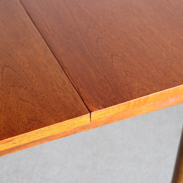 Close-up of vintage teak British mid-century dining table corner showing wood grain and smooth edge.