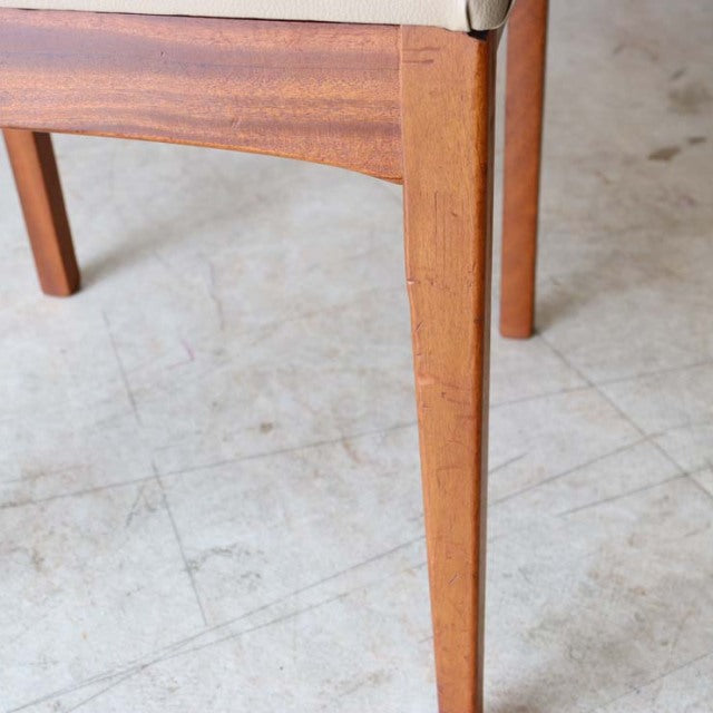 Close-up of mid-century vintage British teak dining chair leg with visible wood grain and smooth finish, showcasing sturdy,.