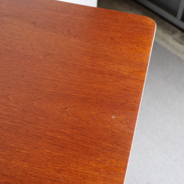 Vintage British mid-century teak dining table corner with smooth wood grain and rounded edge detail.