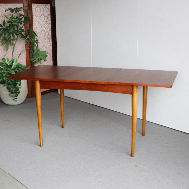 Vintage mid-century British teak dining table with warm wood grain and slender tapered legs from Denmark design tradition.