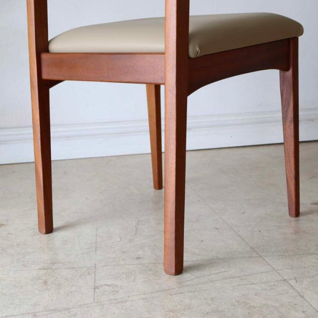 Mid-century vintage teak dining chair with smooth grain, clean lines, and cream upholstered seat.