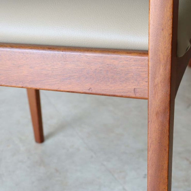 Close-up of teak wood leg and frame with visible grain on a mid-century vintage British dining chair with light beige.