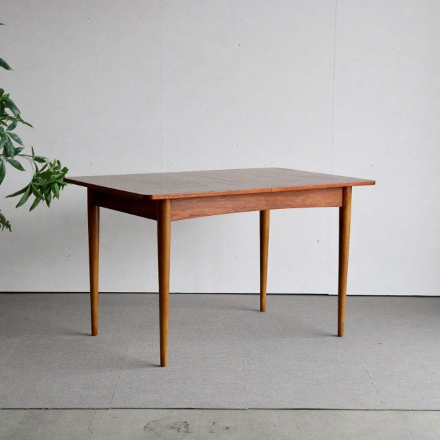 Mid-century British teak dining table with tapered legs and rich wood grain, vintage Denmark style.