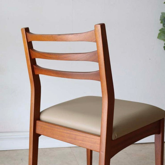 Mid-century vintage teak dining chair with British design, ladder back and beige cushioned seat.