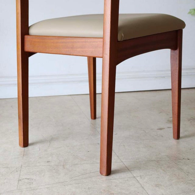 Set of four vintage British mid-century teak dining chairs with white upholstered seats and tapered legs.