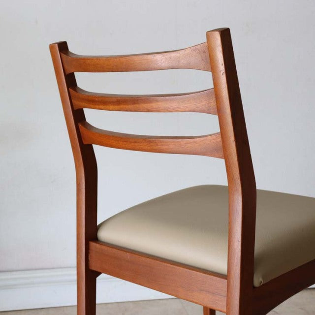 Mid-century vintage British teak dining chair from Denmark with curved slat back and beige upholstered seat.