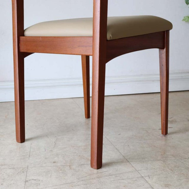Mid-century British vintage teak dining chair with beige upholstered seat and slender tapered legs in a Danish style.