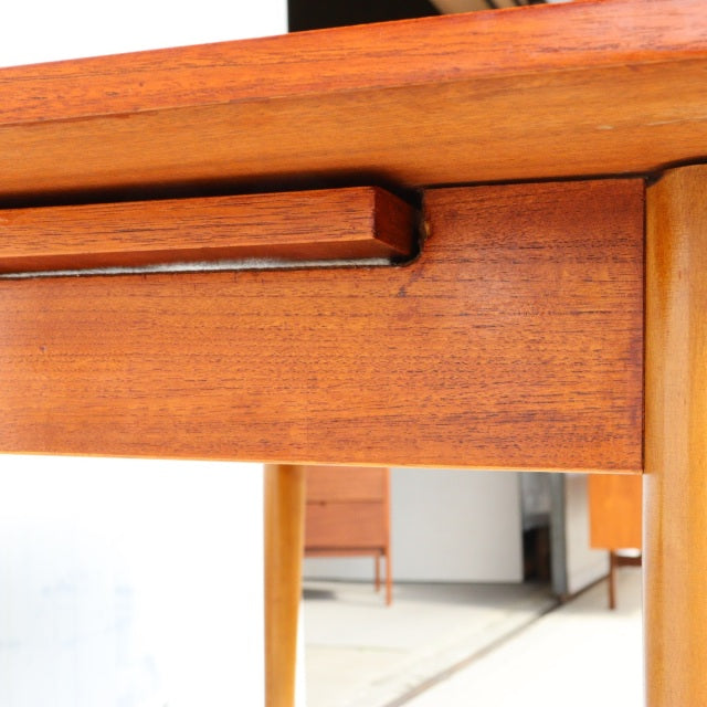Mid-century British vintage teak dining table corner showing rich wood grain, smooth finish, and tapered legs from Denmark.