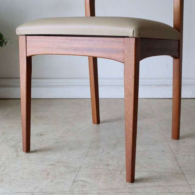 Set of four vintage British mid-century teak dining chairs with white reupholstered seats and slender tapered legs showing.