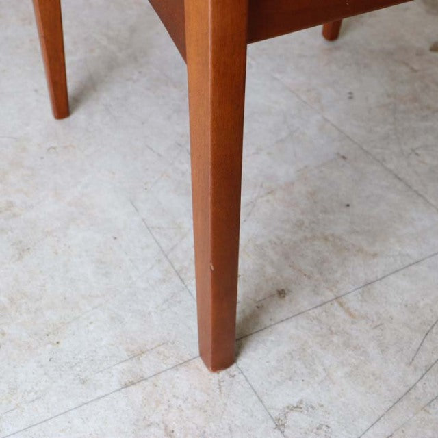 Close-up of vintage teak dining chair leg showing smooth grain and mid-century British craftsmanship with a warm brown finish.