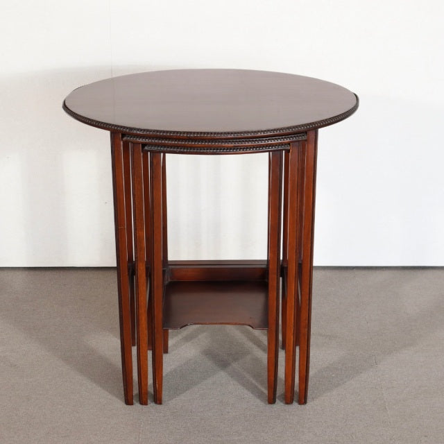 Vintage British mid-century teak nest tables with round tops, tapered legs, and visible wood grain from Denmark.
