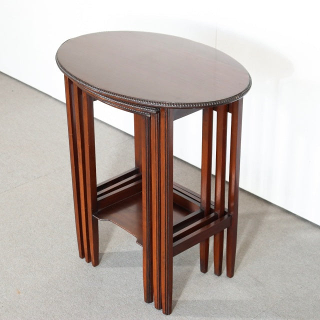 Vintage British mid-century teak nest tables with rounded tops, slender legs, and rich wood grain.