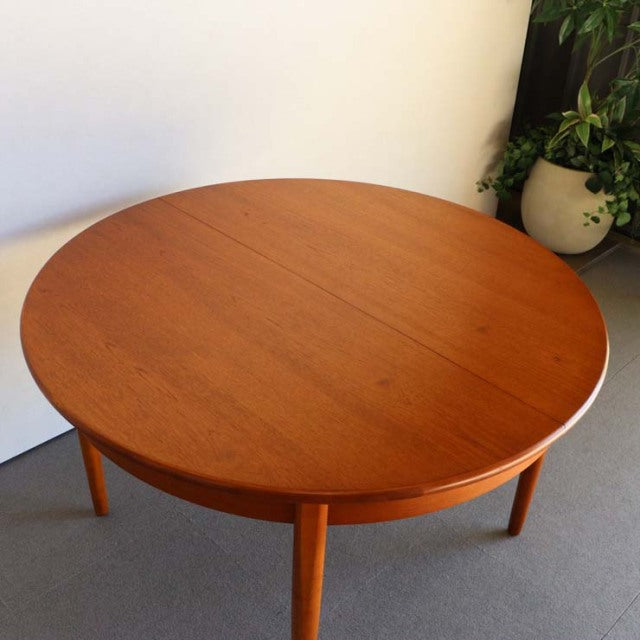 Round vintage teak dining table with smooth wood grain and tapered mid-century British legs.