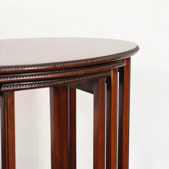 Vintage British mid-century teak nest tables with rich wood grain, rounded edges, and carved detailing on the apron.