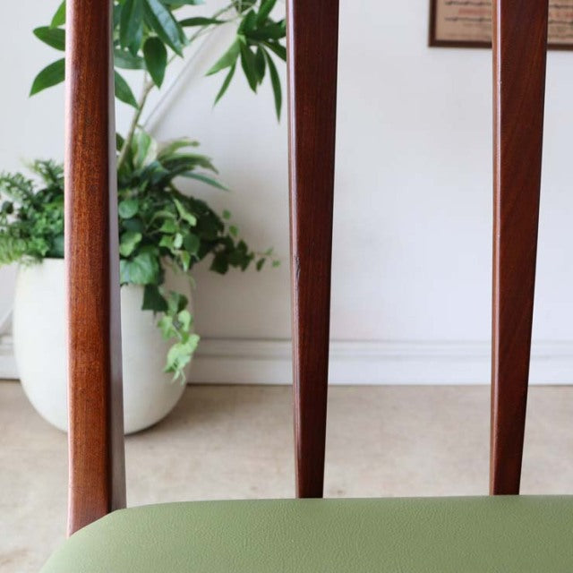 Mid-century British vintage teak dining chair with slender tapered legs and green upholstered seat, showcasing smooth wood.