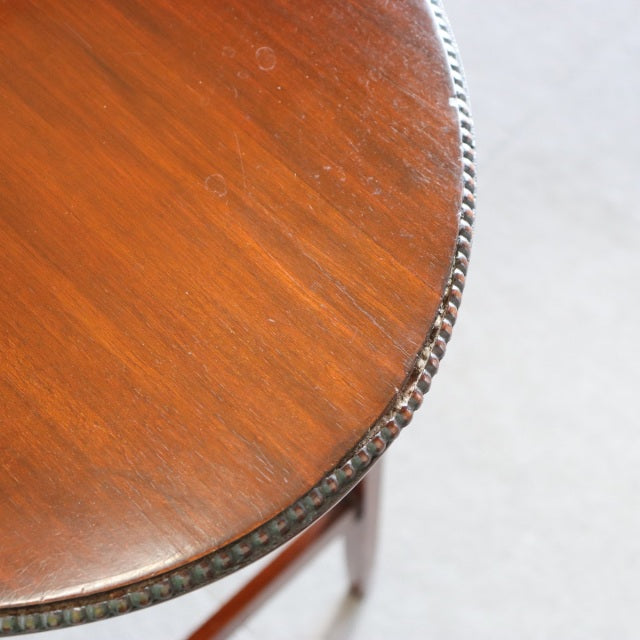 Round vintage teak nest table top with smooth wood grain and carved edge detail, British mid-century style.