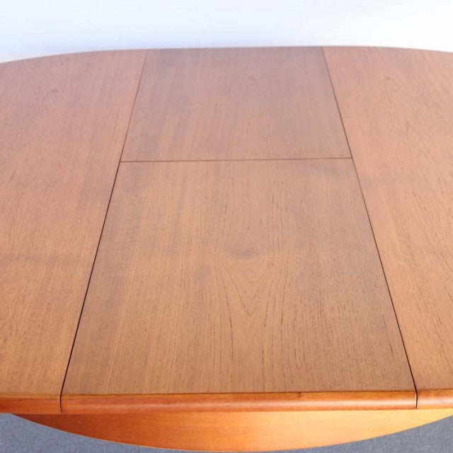 Mid-century British vintage teak round dining table with smooth wood grain and clean edges.