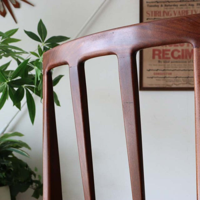 Close-up of vintage teak dining chair backrest with smooth curved top rail and vertical slats, mid-century British design by .