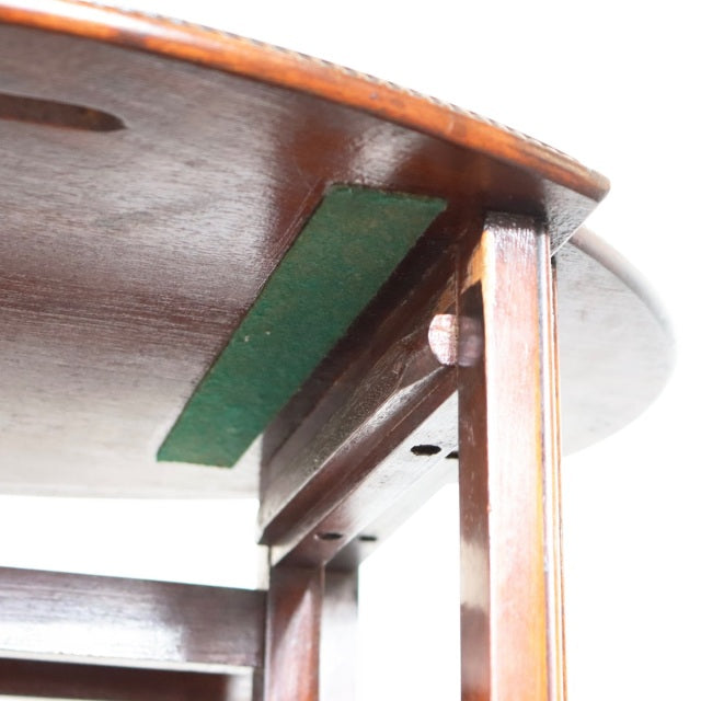 Close-up of vintage British teak nest table leg and underside showing rich wood grain, mid-century craftsmanship, and green.