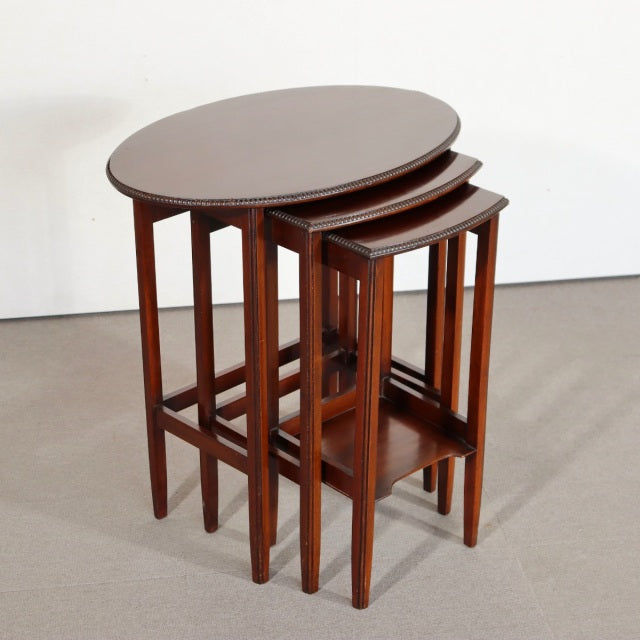 Set of three vintage British mid-century teak nest tables with smooth oval tops, slender straight legs, and visible wood.