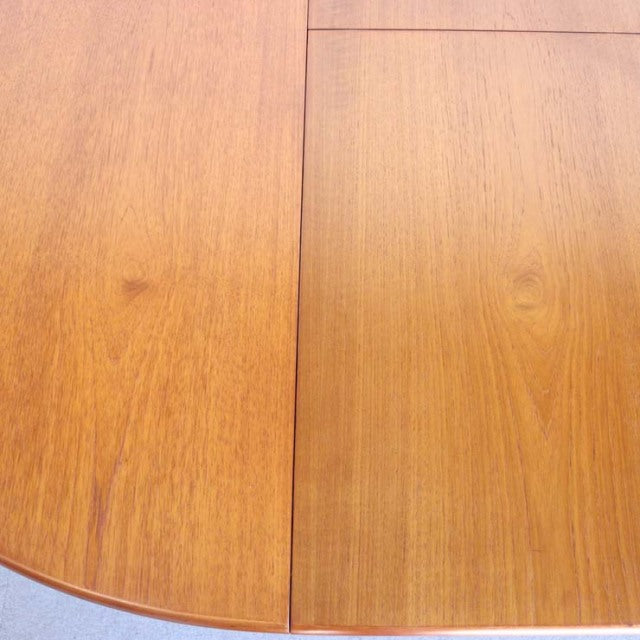 Mid-century British vintage teak round dining table top showing smooth wood grain and warm honey tones.