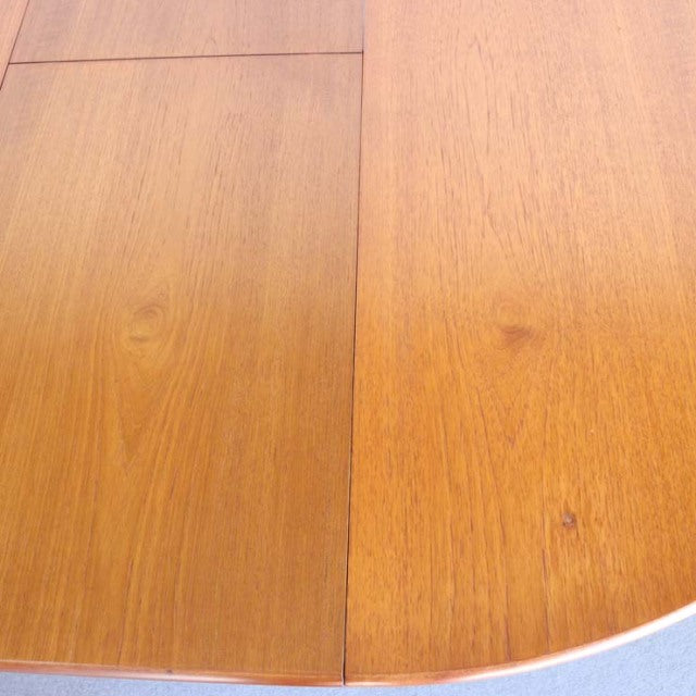Mid-century vintage teak dining table with smooth grain and rounded edges, British design from Denmark.