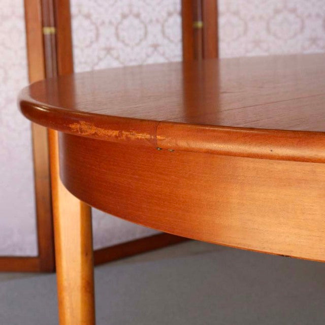 Mid-century British vintage teak round dining table with smooth wood grain and tapered legs.