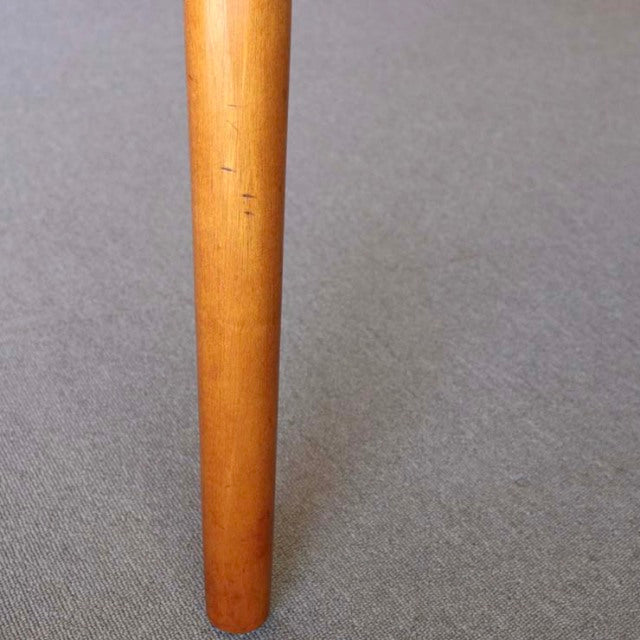 Slim tapered teak leg of mid-century British vintage dining table on neutral carpet.