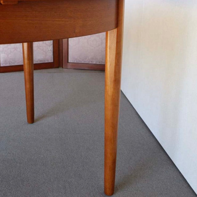 Mid-century vintage British teak round dining table leg with smooth wood grain and tapered design.