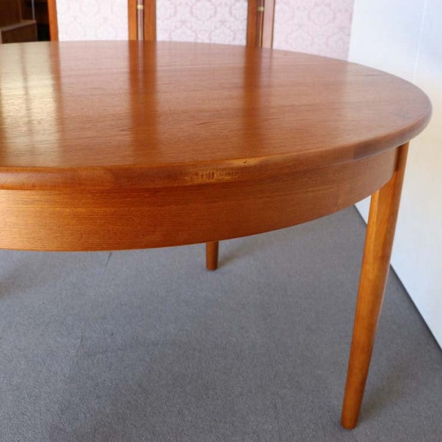Mid-century British vintage round teak dining table with smooth wood grain and tapered legs from Denmark style.