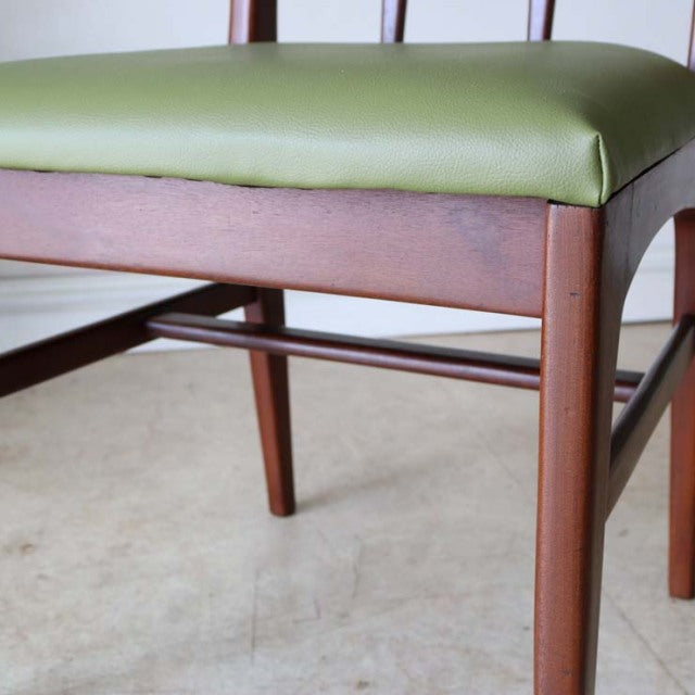 Mid-century British vintage teak dining chair with olive green upholstered seat and slender wooden legs.
