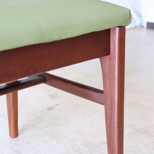 Mid-century British dining chair in vintage teak with tapered legs and light green upholstered seat.