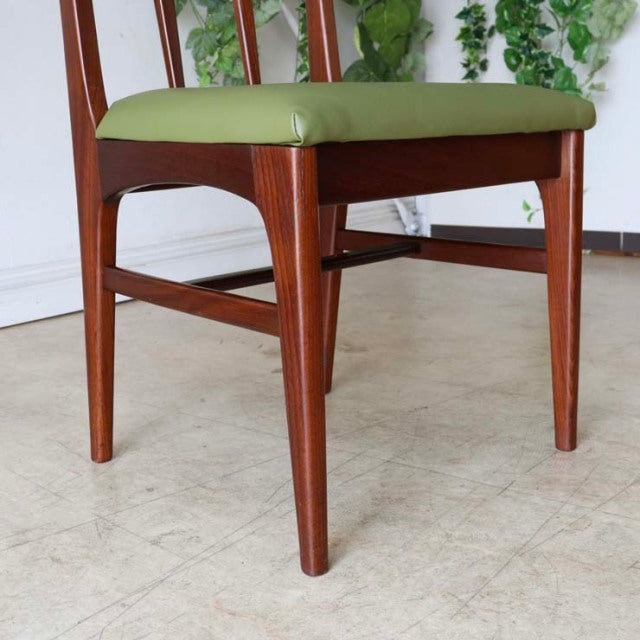 Mid-century British dining chair in vintage teak with olive green cushioned seat and tapered legs.