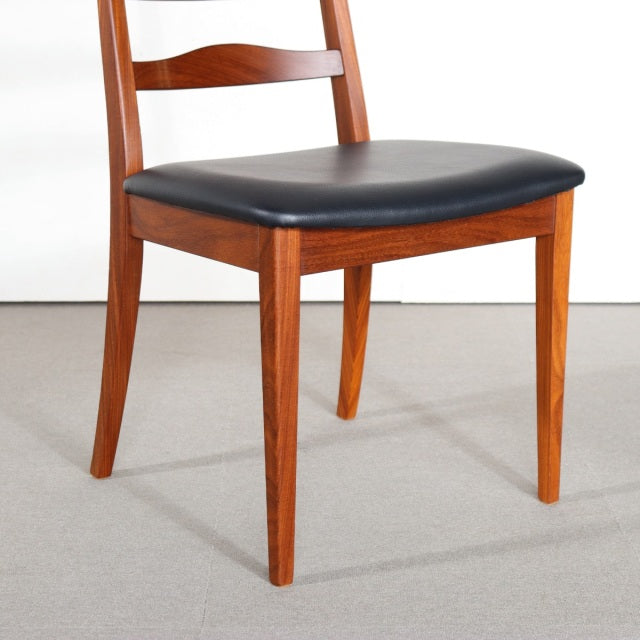 Vintage British mid-century G-plan teak dining chair with black cushioned seat and sleek wood grain legs.