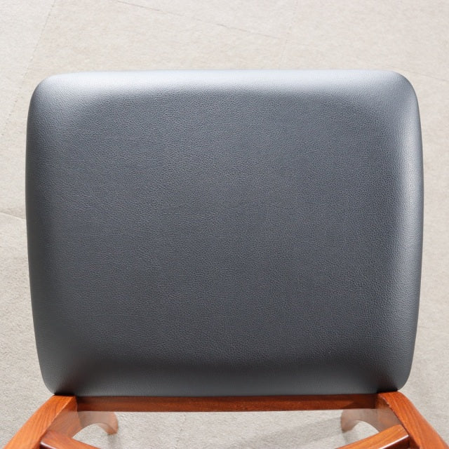 Mid-century British G-Plan dining chair backrest with smooth dark gray leather upholstery above teak wood frame.