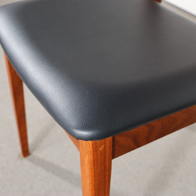 Vintage British G-Plan mid-century dining chair with teak frame and black leather seat, showcasing clean lines and rich wood .