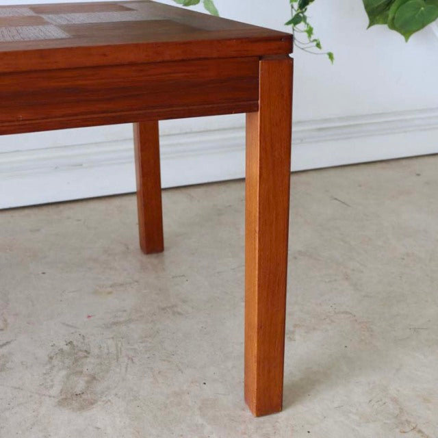 Mid-century British teak coffee table leg with visible wood grain and clean lines on concrete floor.