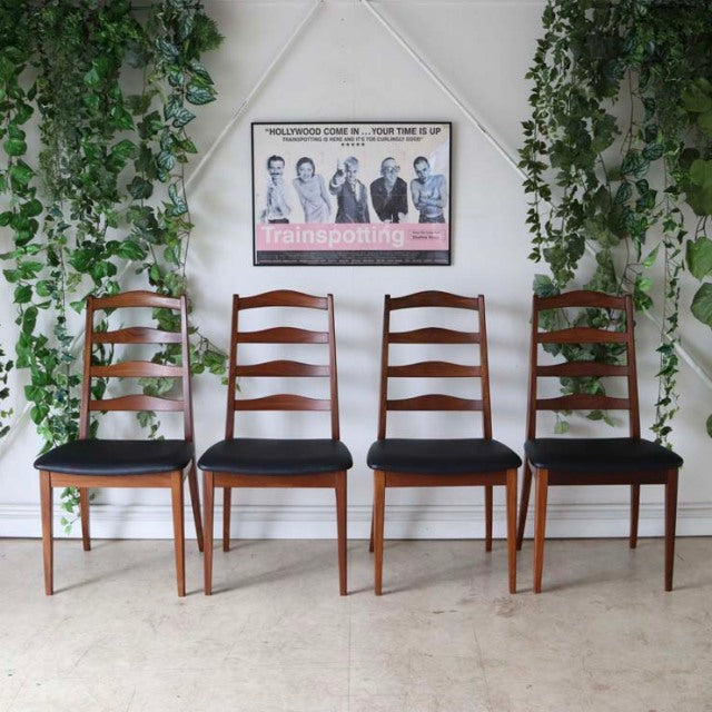 Set of four vintage G-Plan teak ladder-back dining chairs with black upholstered seats, mid-century British design inspired.