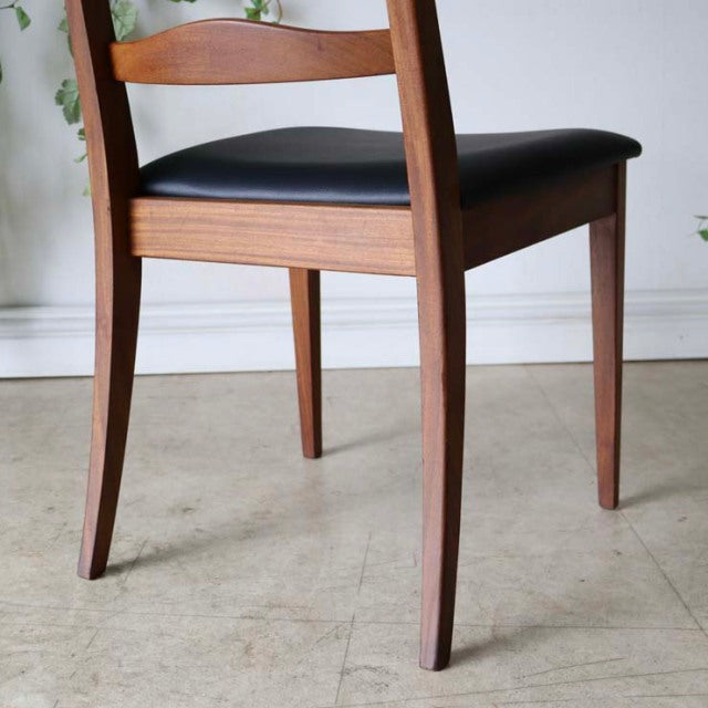 Set of four vintage British G-Plan teak mid-century ladder back dining chairs with black cushioned seats and tapered legs.