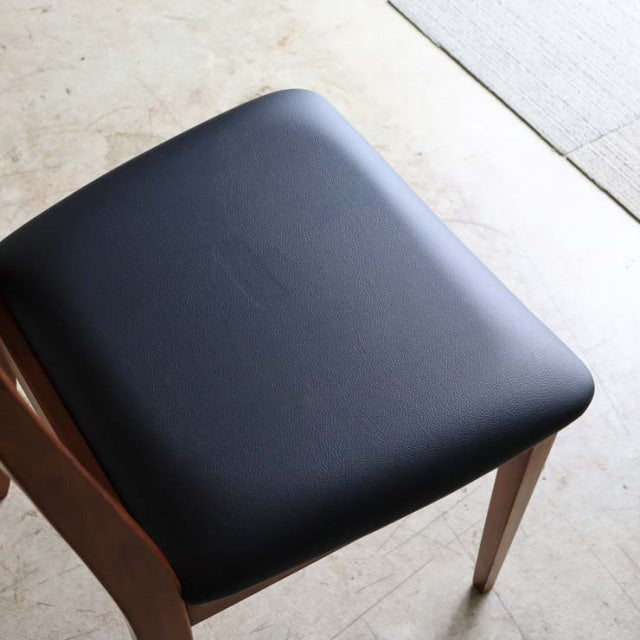 Set of four G-Plan mid-century British vintage teak dining chairs with black cushioned seats and ladder back design.
