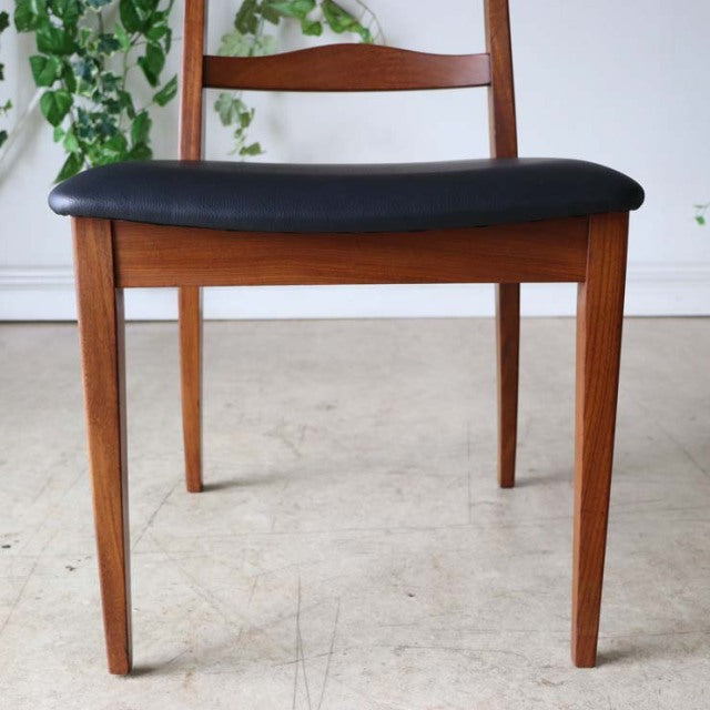Set of four vintage G-Plan mid-century teak ladder back dining chairs with black cushioned seats and tapered legs.