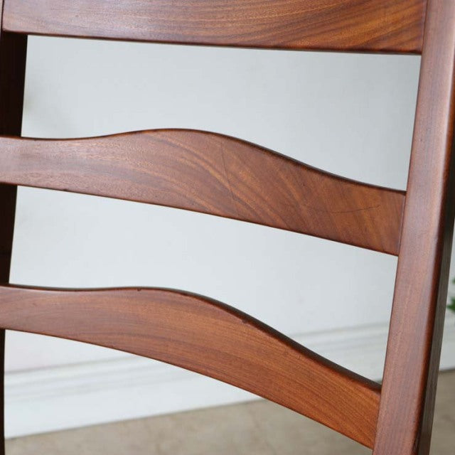 Set of four vintage British mid-century teak ladder back dining chairs with curved slats and rich wood grain.