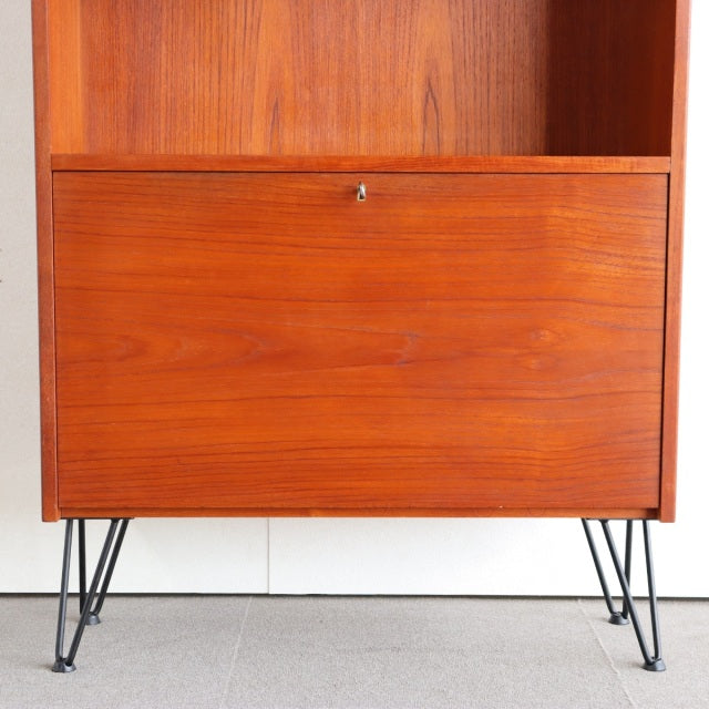 Mid-century vintage teak cabinet with smooth wood grain, sleek iron legs, Danish-British design blend.