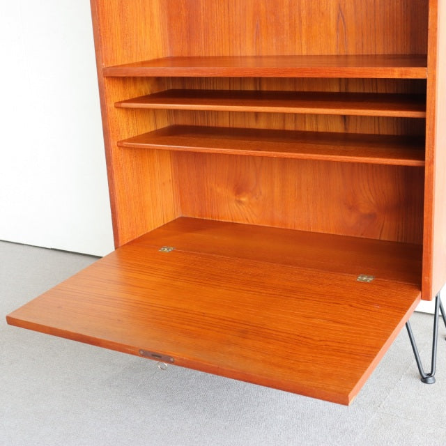 Mid-century vintage teak cabinet from Denmark with rich wood grain, iron legs, and drop-down door panel.